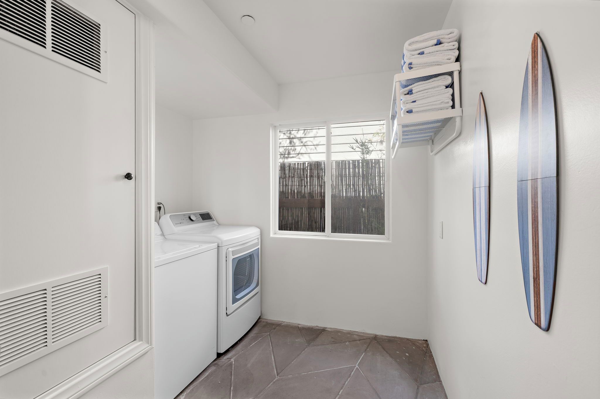Une buanderie équipée d’un lave-linge, d’un sèche-linge et de piles de serviettes.