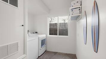 Une buanderie équipée d’un lave-linge, d’un sèche-linge et de piles de serviettes.