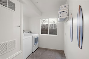 Une buanderie équipée d’un lave-linge, d’un sèche-linge et de piles de serviettes.