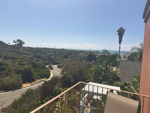 A balcony with a view of a winding road through a forested area, leading to a coastline. - Quiet Retreat w/ Coastal View + Walk to Beach (San Clemente)