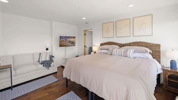 Une chambre avec un grand lit, un canapé, une télévision et des œuvres d’art accrochées au mur.