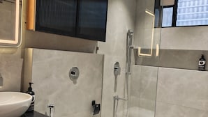 A modern bathroom with a white toilet, a large sink, a shower enclosure, and a mirror with a light. - Majestic Park Inn (Vapi)