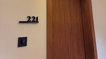 A hotel room with a wooden door, a number sign, and a light switch.