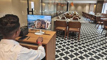 A hotel lobby with a large monitor displaying a scenic view, a reception desk, and a patterned floor.