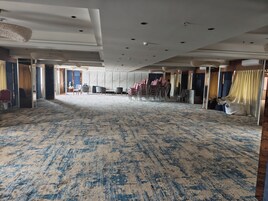 Un'ampia sala con tappeto decorato, file di sedie e un soffitto alto con illuminazione a incasso.
