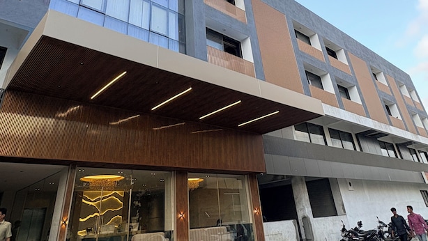 A modern building with a glass facade, wooden paneling, and a covered entrance. - Majestic Park Inn (Vapi)