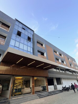 A modern building with a glass facade, wooden paneling, and a covered entrance. - Majestic Park Inn (Vapi)