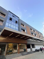 Un edificio moderno con fachada de vidrio, paneles de madera y un acceso cubierto.