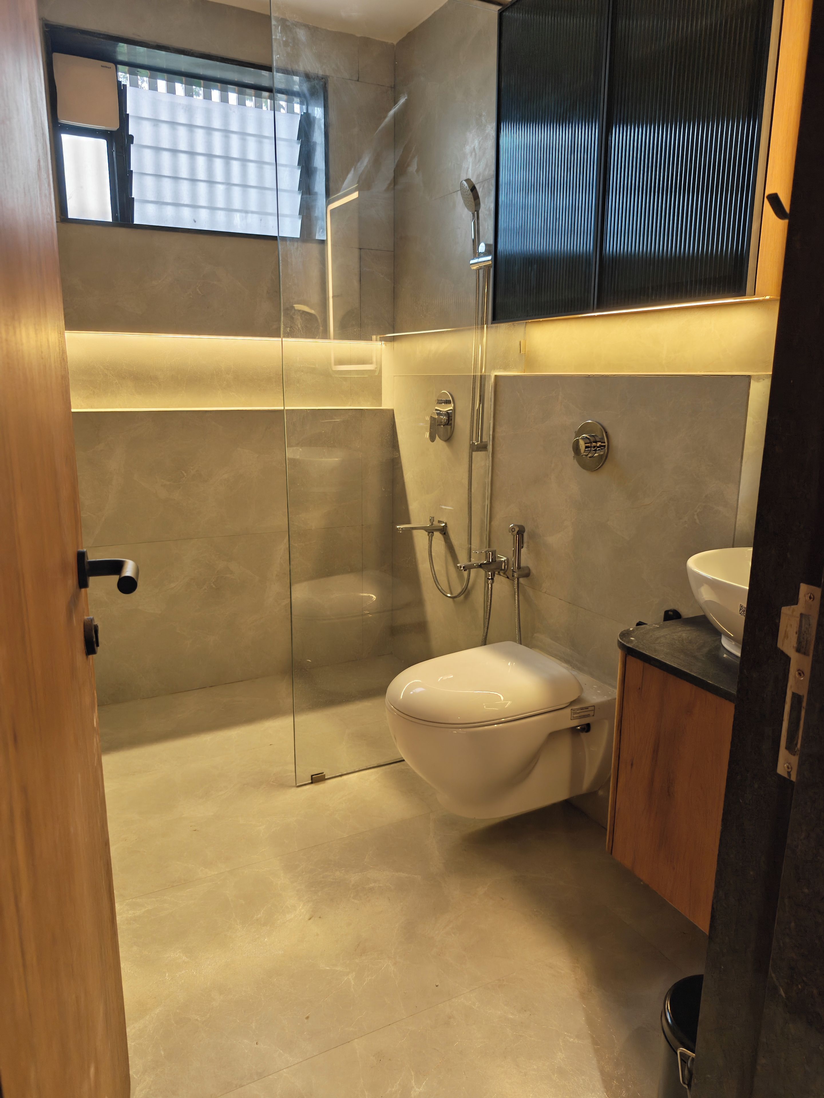 A modern bathroom with a glass shower enclosure, a toilet, and a sink.