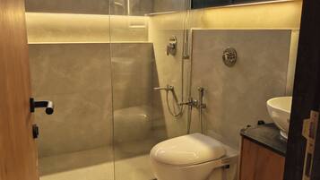 A modern bathroom with a glass shower enclosure, a toilet, and a sink.