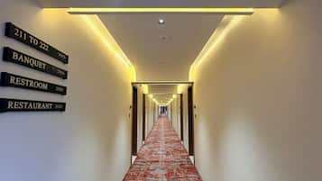 Un corridoio d'hotel con segnali direzionali per le camere 211-222, una sala ricevimenti, un bagno e un ristorante.
