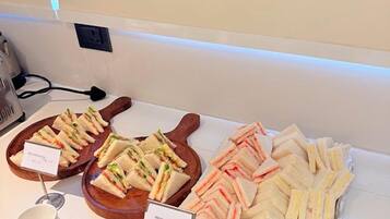 A buffet with labeled food options including sandwiches and bread butter.