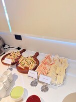 A buffet with labeled food options including sandwiches and bread butter.