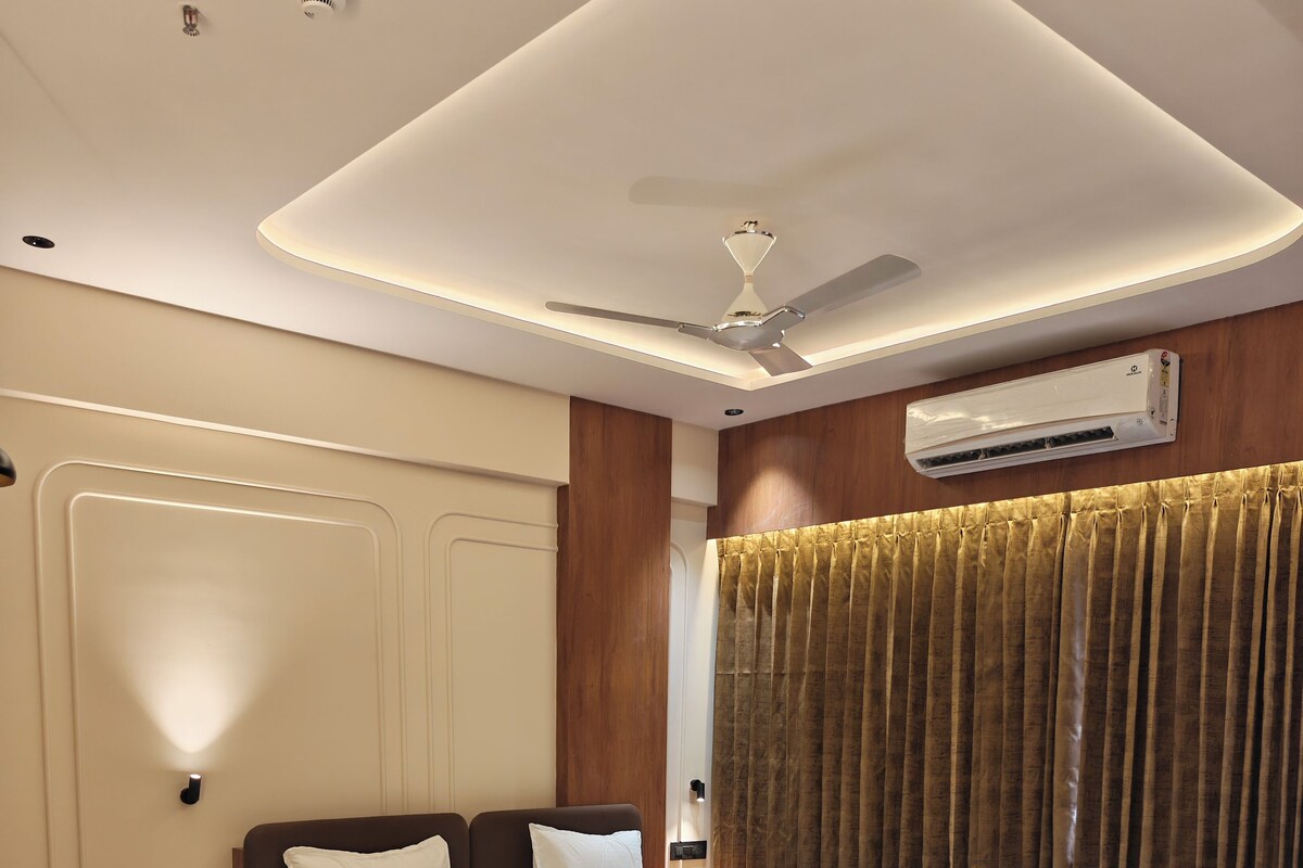 A modern bedroom with a large bed, bedside tables, a ceiling fan, and an air conditioning unit.