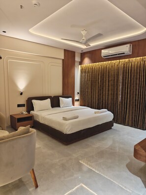 A modern bedroom with a large bed, bedside tables, a ceiling fan, and an air conditioning unit. - Majestic Park Inn (Vapi)