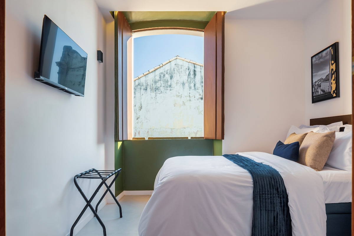Ein Hotelzimmer mit Bett, Fernseher, Fenster mit Bergblick und einem Bild an der Wand.