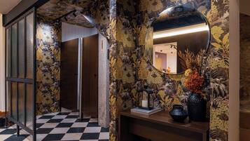 Un pasillo con piso a cuadros, un espejo y una pared con estampado floral.