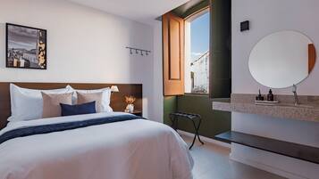 A modern bedroom with a bed, bedside table, lamp, and a view of the outside.