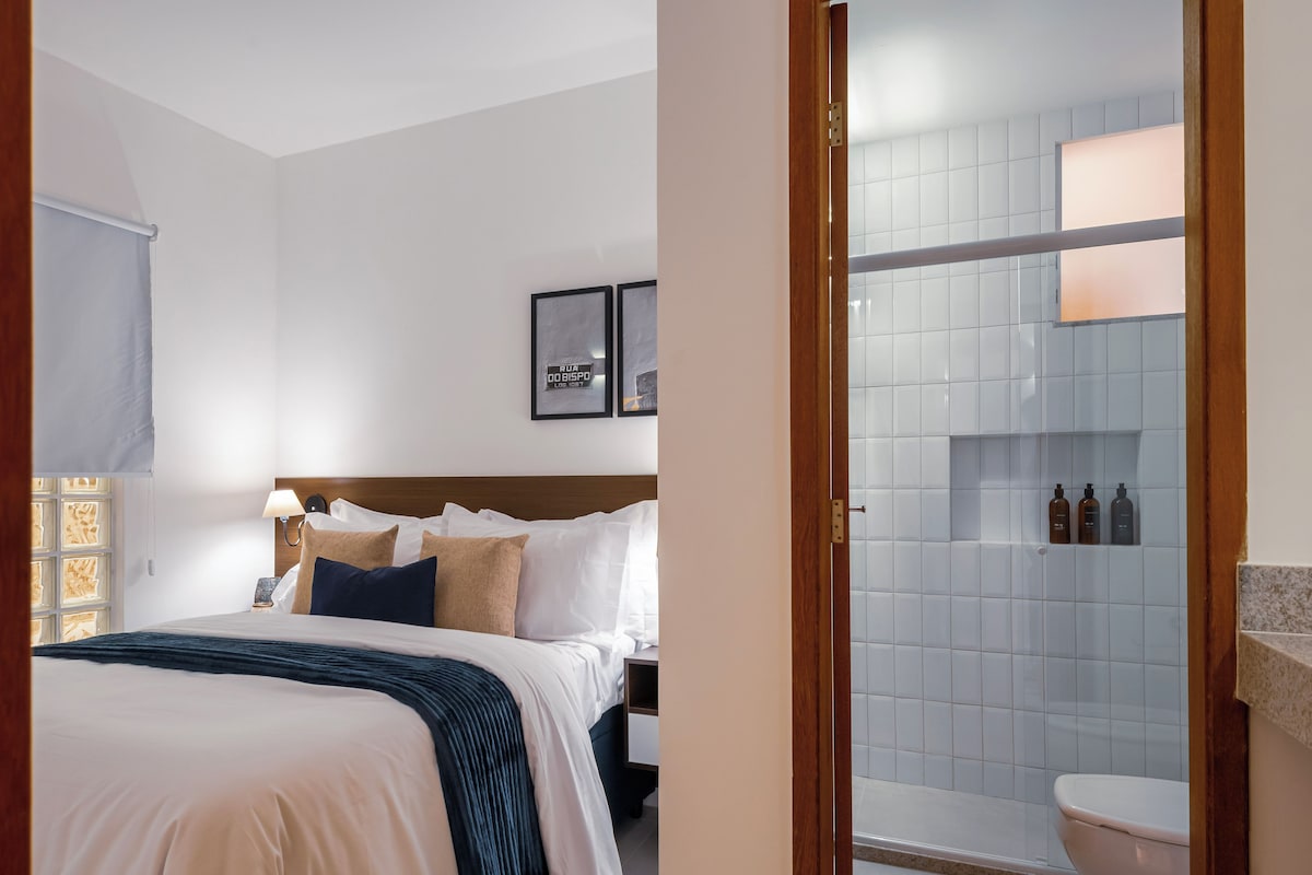 Ein Hotelzimmer mit Bett, Nachttisch und einem Badezimmer mit Dusche und Toilette.