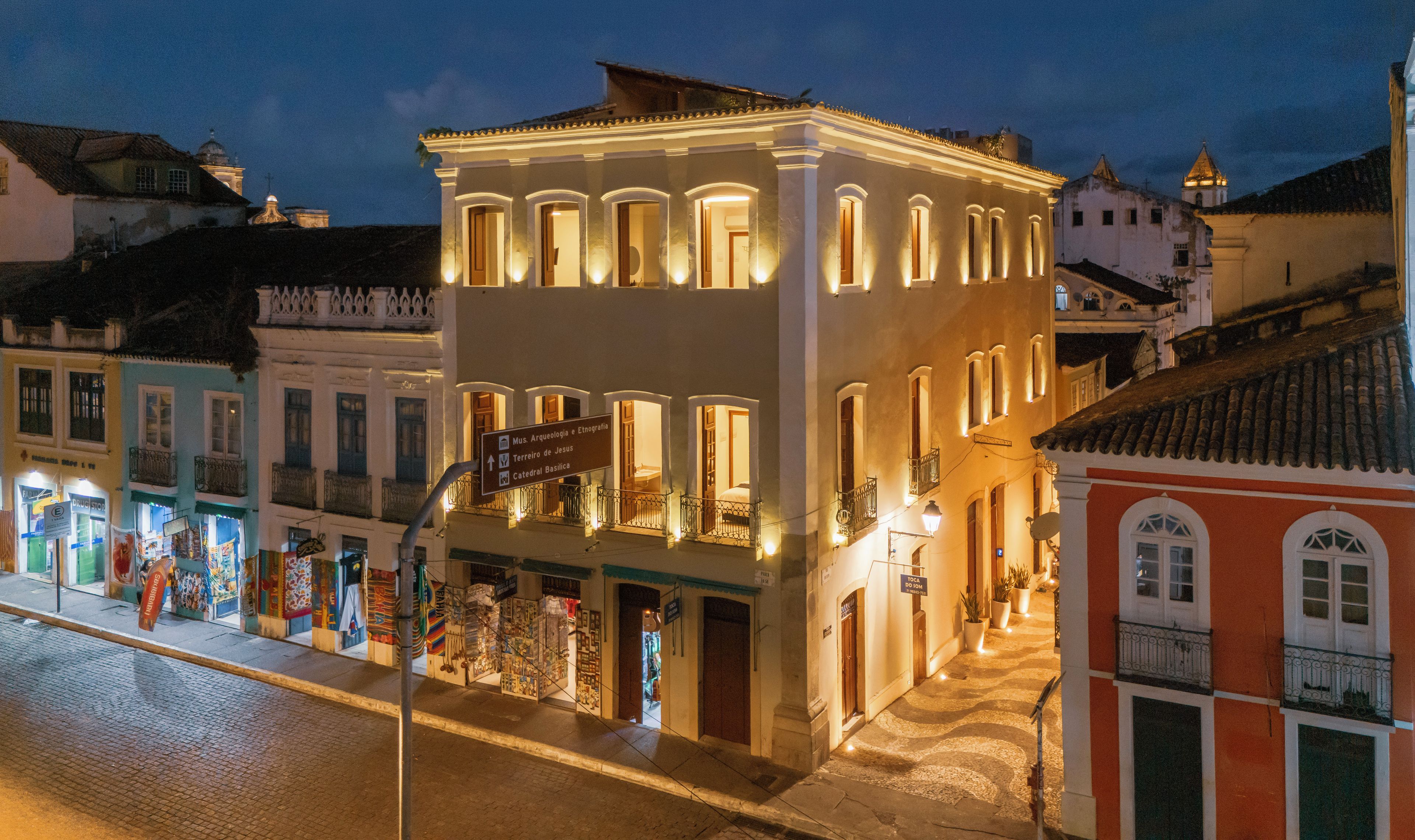 Un edificio histórico con ventanas y balcones iluminados, un cartel que indica un museo, y una calle adoquinada.