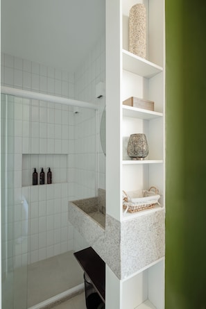Ein Badezimmer mit Dusche, Waschbecken und Regalen mit Pflegeprodukten.