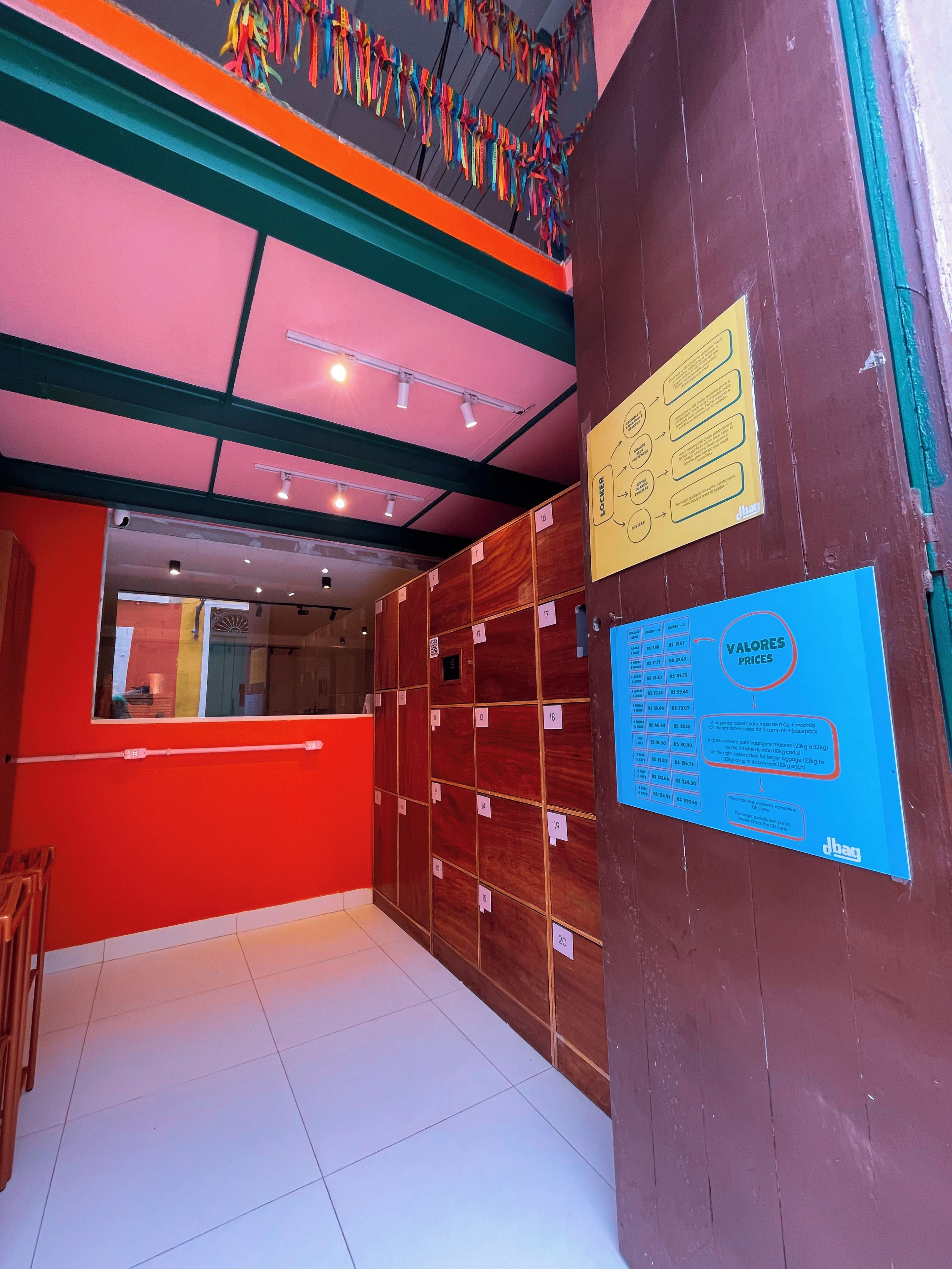 Habitación de hotel con pared roja, zona de armarios de madera y cartel informativo azul.