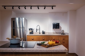 Una cocina moderna con un refrigerador de acero inoxidable, una tetera y una tabla de cortar con verduras.
