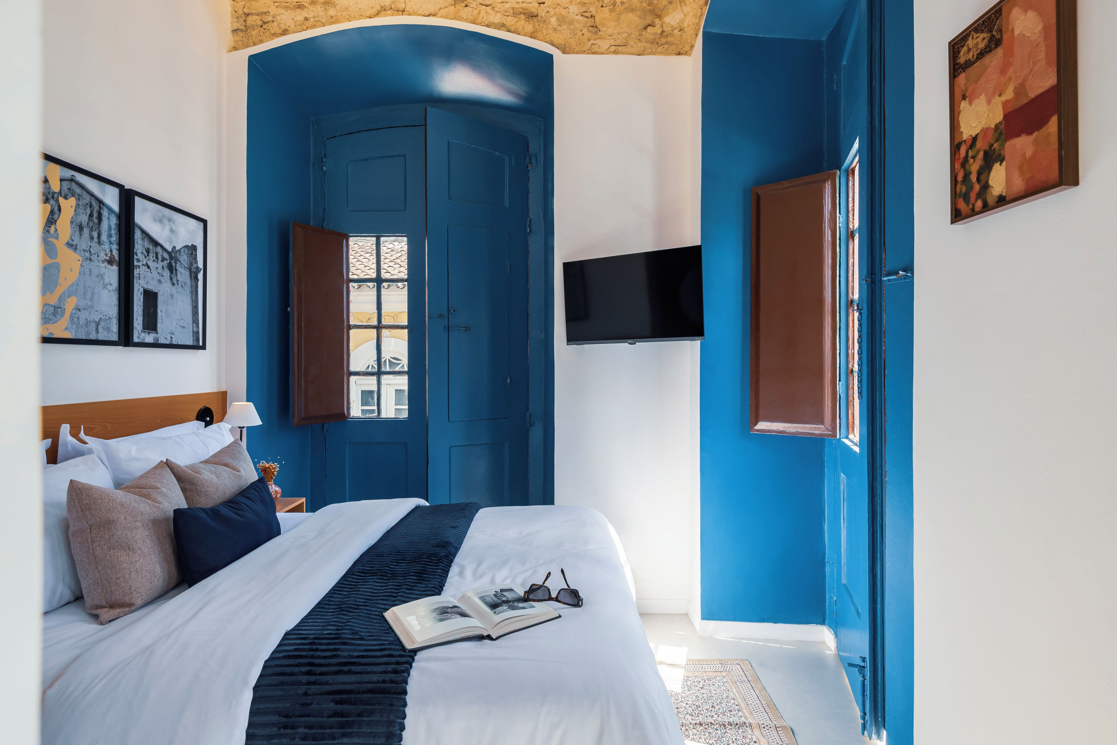 Een slaapkamer met een groot bed, een flatscreen televisie aan de muur en een raam met uitzicht.