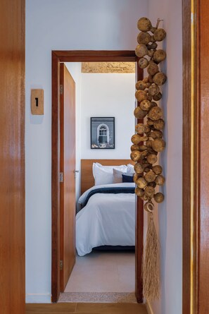 A hotel room with a bed, a framed picture on the wall, and a wooden door with a number 1 sign.