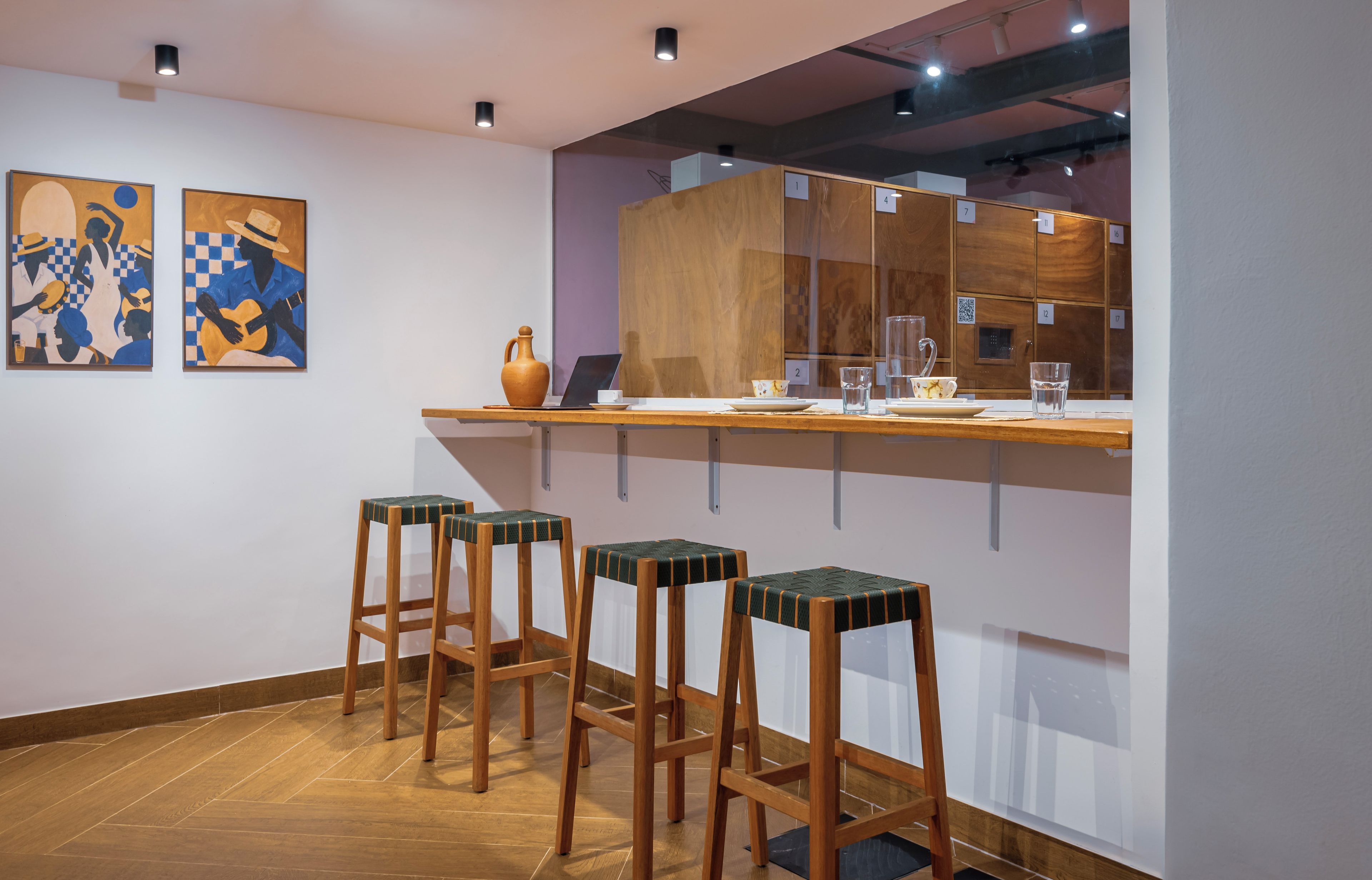 Un área de bar moderna con taburetes de madera, una computadora portátil y un florero.