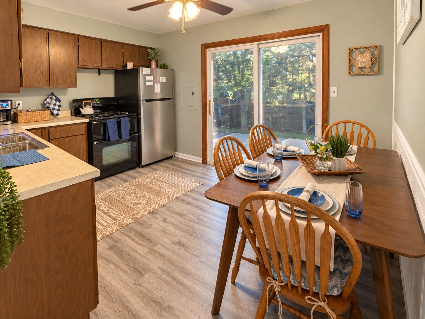 A kitchen with wooden cabinets, a refrigerator, and a dining area with a table set for four.