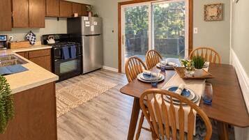 A kitchen with wooden cabinets, a refrigerator, and a dining area with a table set for four.