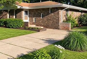 A two-story brick house with a front porch, a well-maintained lawn, and a driveway. - Dunes & Beach Getaway - Sleeps 10 - Room for the Whole Crew (Portage)