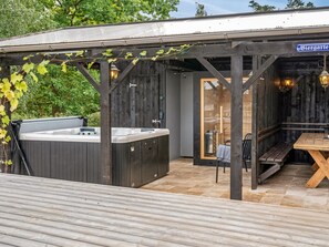 Een houten zitgedeelte buiten met een jacuzzi en een tafel.