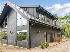 Ein modernes, zweistöckiges Haus mit großen Fenstern und einer überdachten Veranda.