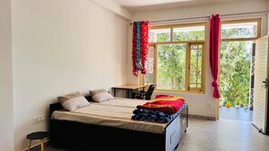 A bedroom with a bed, a desk, and a window with curtains.