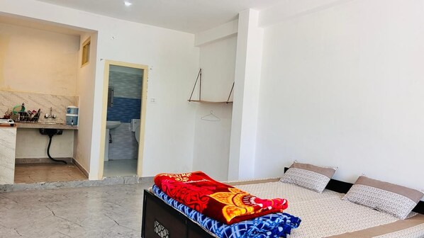 Un dormitorio con una cama, una mesita de noche y un baño visible a través de una puerta abierta.