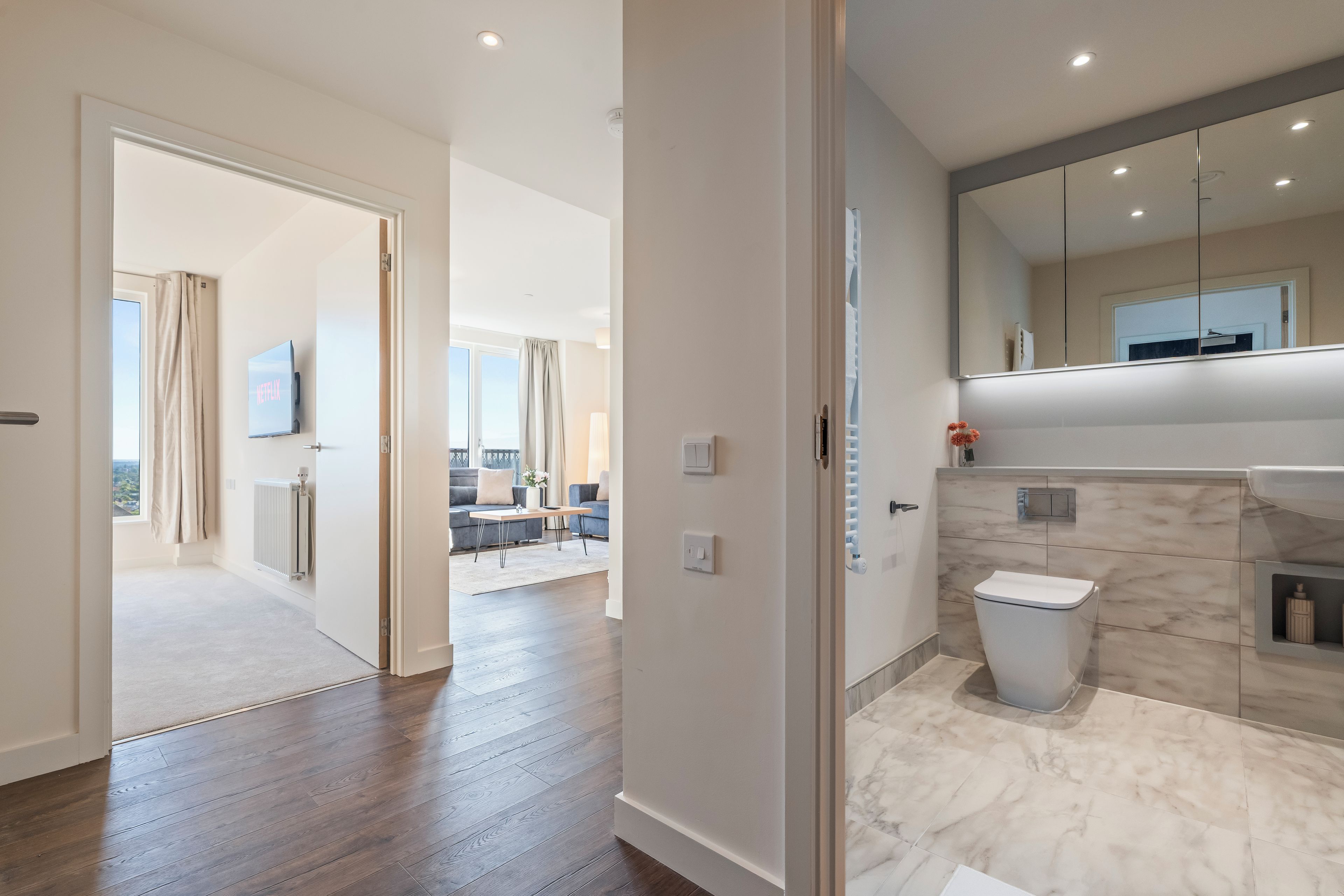 A modern bathroom with a toilet, sink, and mirror.
