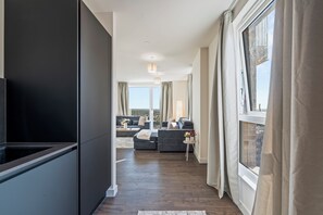 Un intérieur moderne comprenant une cuisine, un espace de vie et de grandes fenêtres.