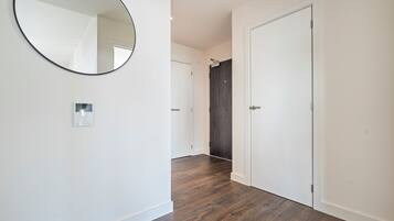 A hallway with a round mirror, a light switch, and a door with a dark wood finish.