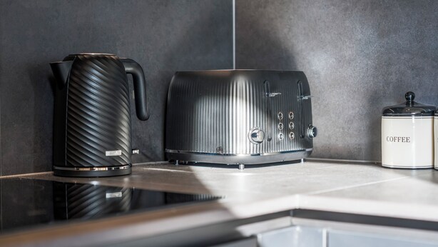 Eine Küche mit Kaffeemaschine, Wasserkocher und Toaster auf einer Arbeitsplatte.