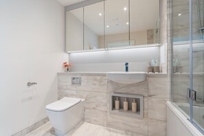 Une salle de bain moderne équipée de toilettes, d’un lavabo et d’une douche.