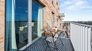 Ein Balkon mit Tisch und Stühlen, einem Blumentopf und Blick auf die Stadt.