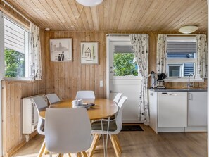 A cozy kitchen with wooden walls, a dining area with a round table and chairs, and a view of greenery outside. - "Helrun" - 800m from the sea by Interhome (Hejls)