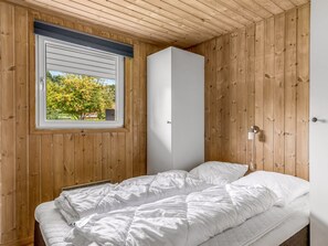 A bedroom with a bed, a window with a view of trees, and wooden walls. - "Helrun" - 800m from the sea by Interhome (Hejls)
