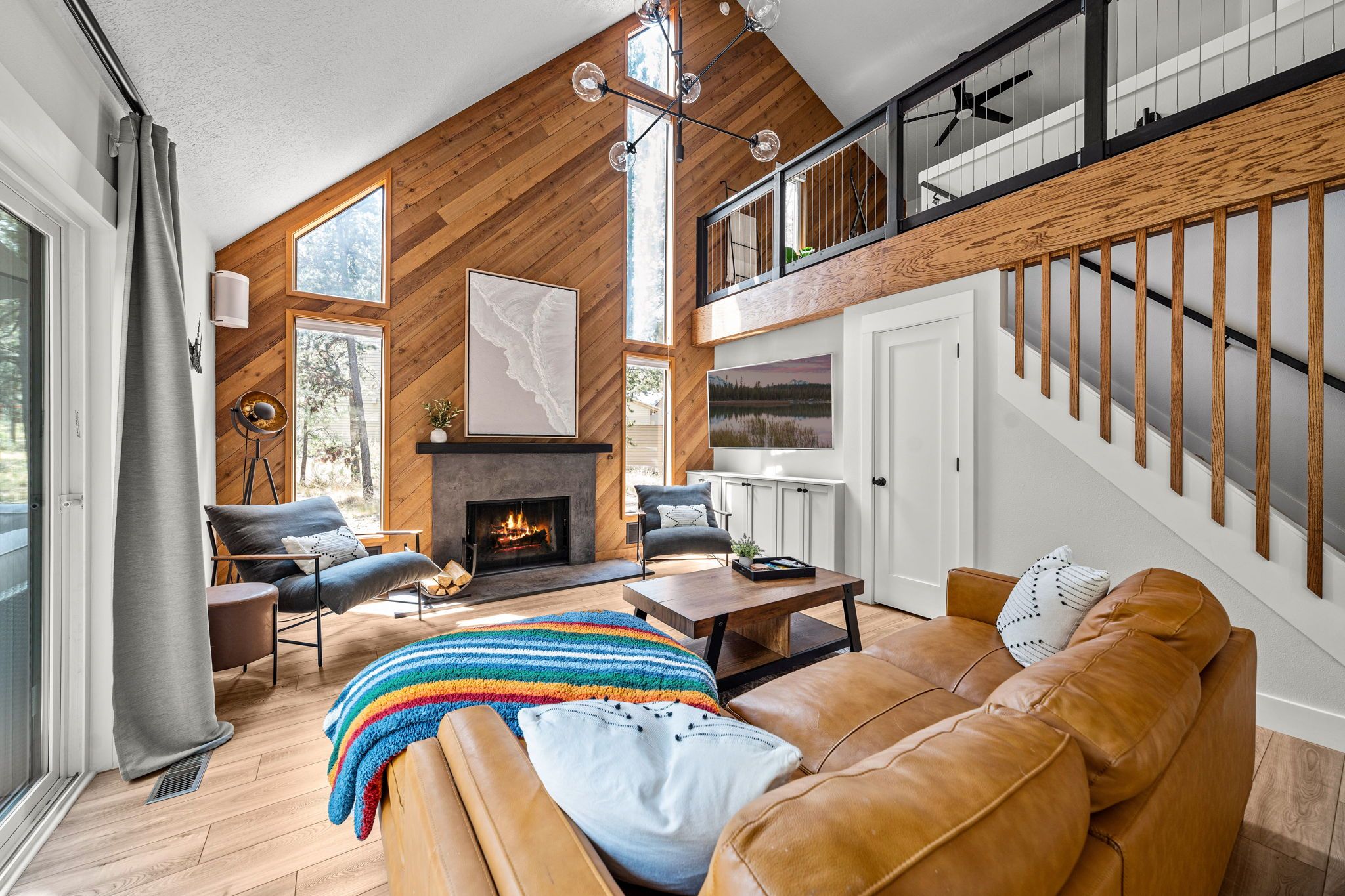 A modern living room with a fireplace, leather sofa, and a staircase.