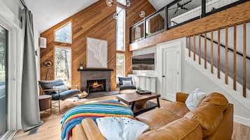 A modern living room with a fireplace, leather sofa, and a staircase.