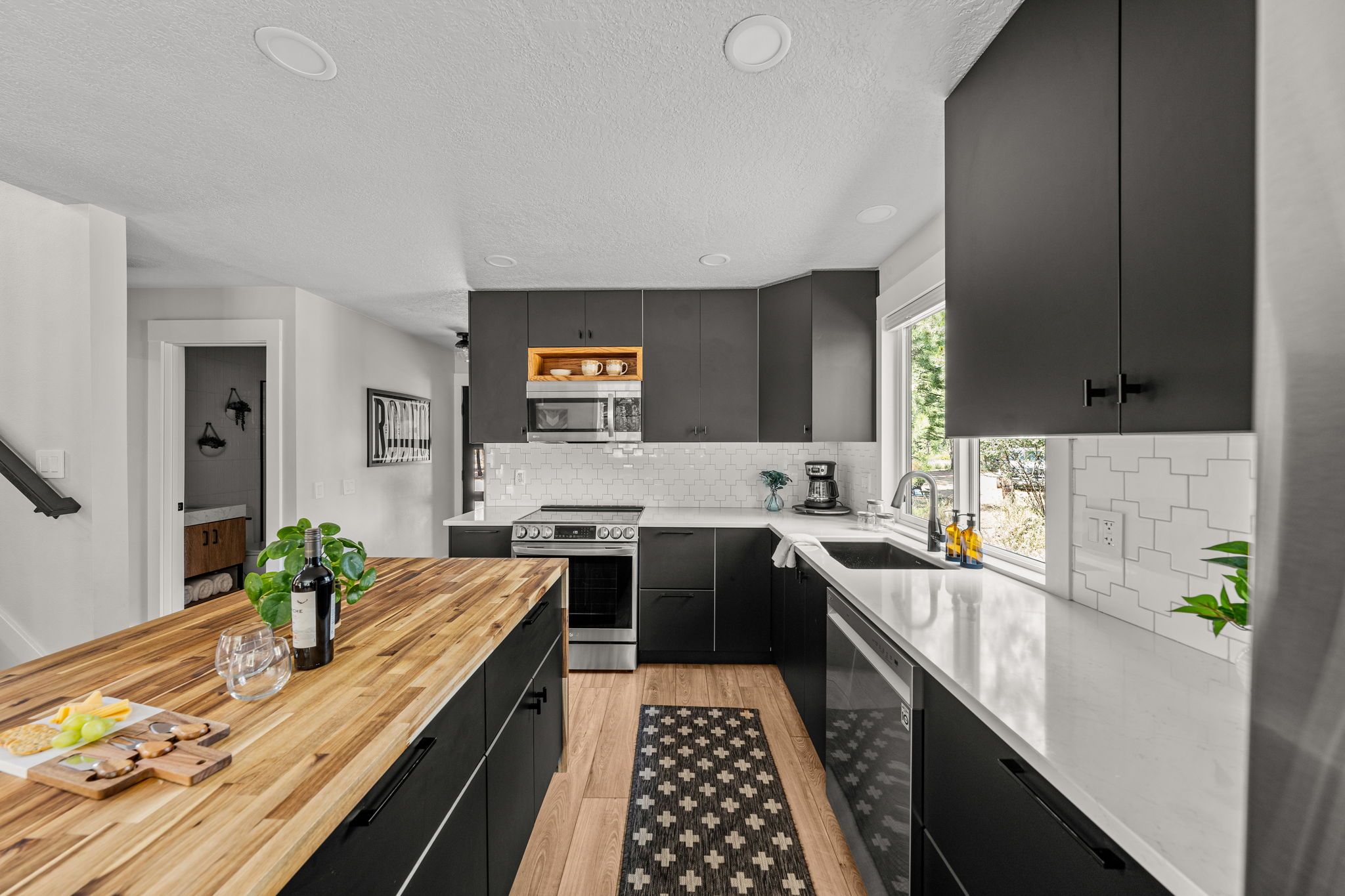 Eine moderne Küche mit dunklen Schränken, einer Holz Arbeitsplatte und einem eingebauten Backofen.
