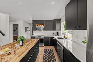 Eine moderne Küche mit dunklen Schränken, einer Holz Arbeitsplatte und einem eingebauten Backofen.