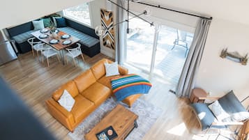 A spacious living area with a sofa, coffee table, and a dining table set for four.